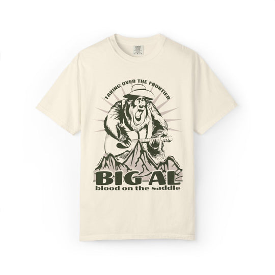 Big Al On The Frontier Tee in Ivory, front flat lay with Big Al, Blood on the Saddle text and mountains