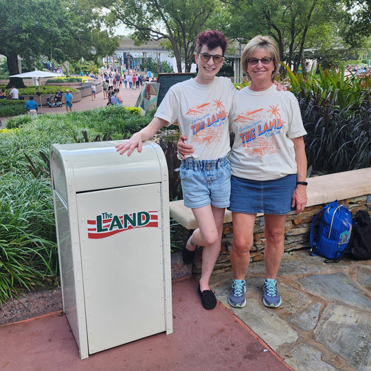 Kylie and a friend in matching Land Pavilion Tees beside a The Land trash can at Epcot