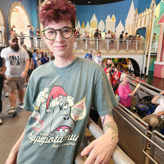Kylie smiling in the Blue Spruce Hippopotamus for Christmas Shirt in the it's a small world queue