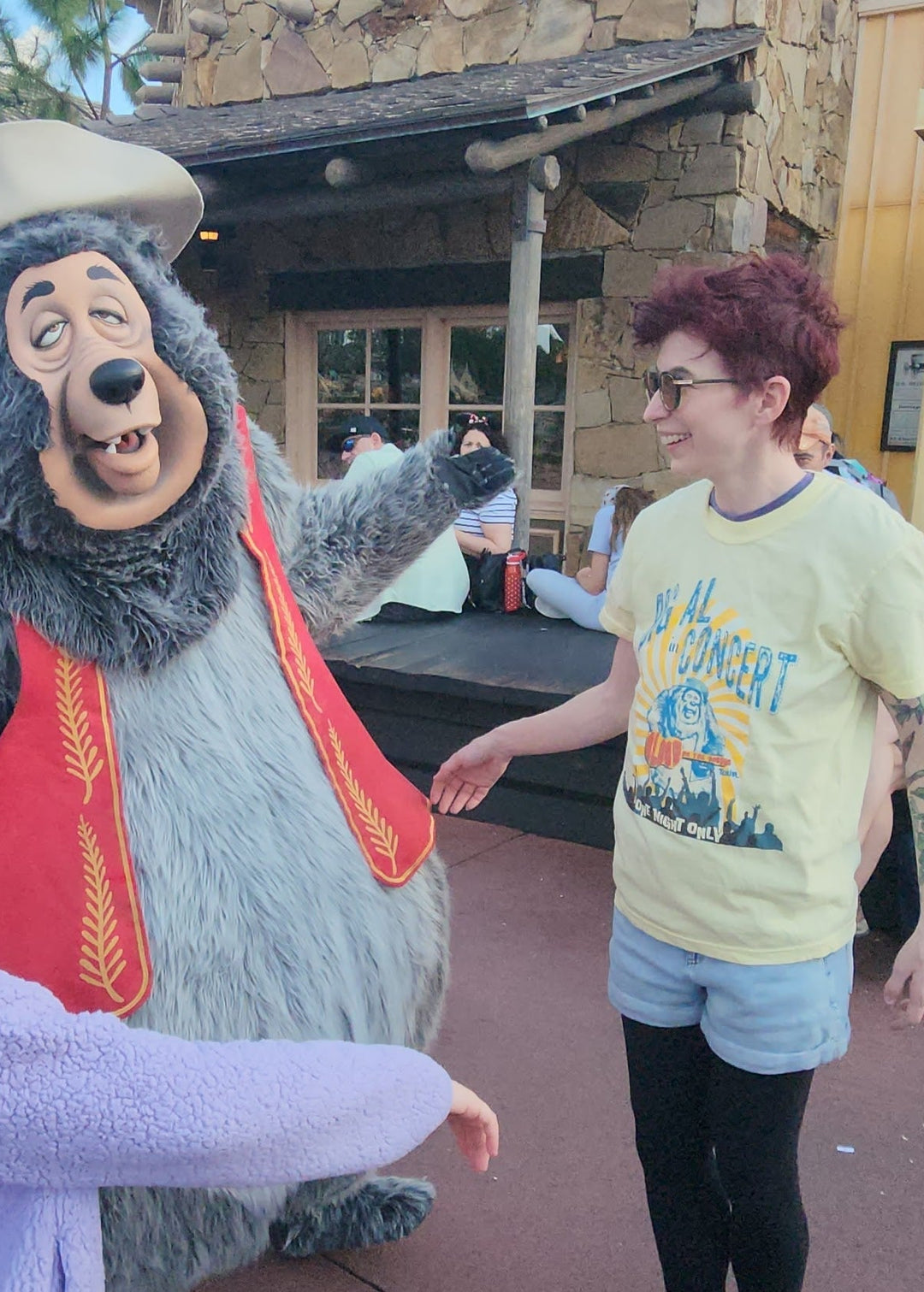 Kylie wearing the Big Al In Concert Tee in Butter, greeting the Big Al character at Magic Kingdom