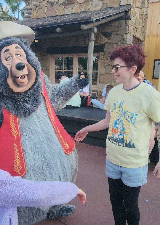 Kylie wearing the Big Al In Concert Tee in Butter, greeting the Big Al character at Magic Kingdom