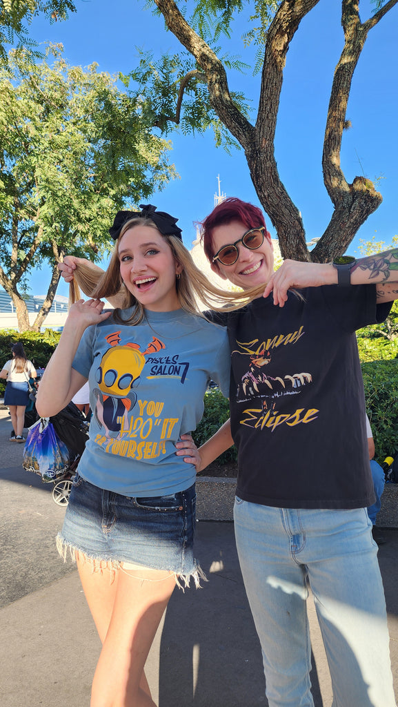 Sonny Eclipse Tee worn by a woman with short red hair posing with a friend under a tree in the park