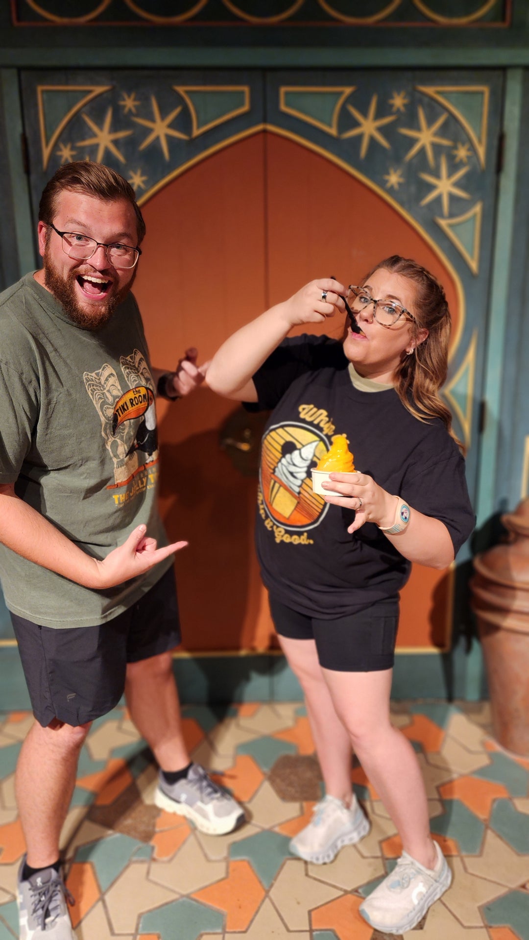 Dole Whip Tee worn by a couple sharing a Dole Whip in front of an ornate Adventureland-style doorway