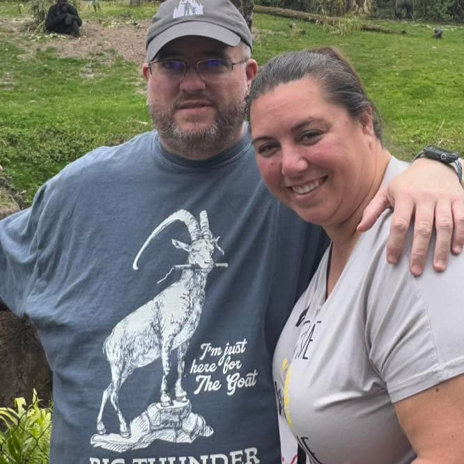 Big Thunder Goat Tee in Navy worn by a man posing with a woman outdoors, close-up of the goat print
