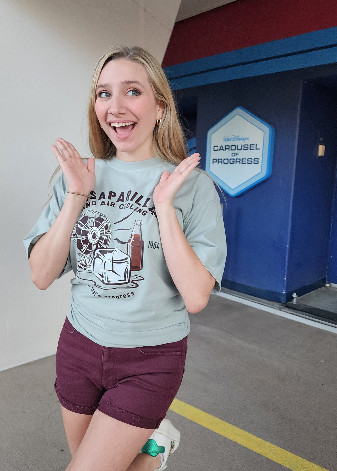 Carousel of Progress Tee in Bay worn by an excited woman outside the Carousel of Progress in Tomorrowland