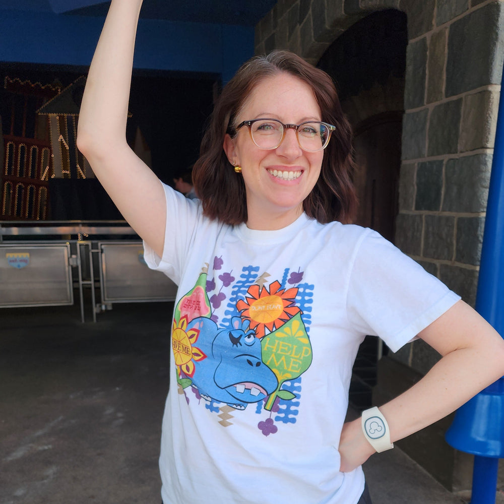 Woman in the Hippo Help Me Tee standing in front of "It's a Small World" 