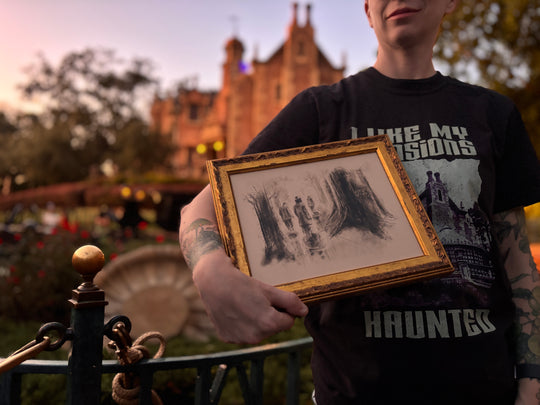 Quicksand Trio Fine Art Print in a small gold frame held in front of the Haunted Mansion, close-up