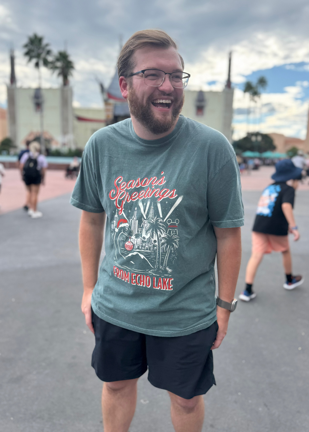 Season's Greetings from Echo Lake Shirt worn by a smiling man in glasses at Hollywood Studios