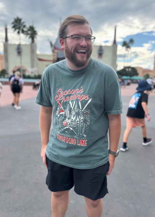 Season's Greetings from Echo Lake Shirt worn by a smiling man in glasses at Hollywood Studios