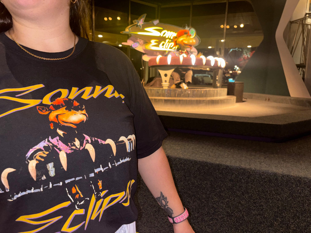 Close-up of the Sonny Eclipse Tee print worn in front of the Sonny Eclipse stage at Cosmic Ray&