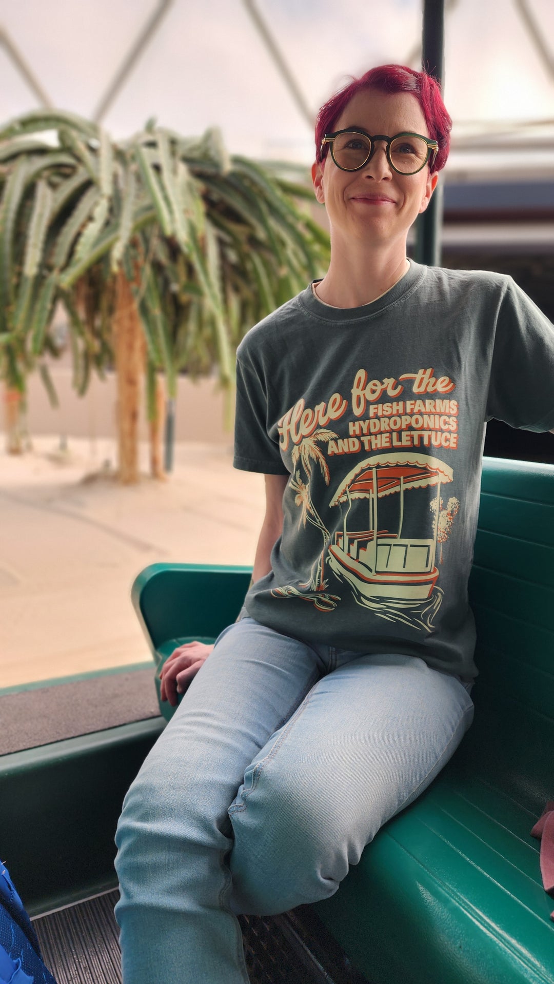 Kylie wearing the Living with the Land Hydroponics Tee in Blue Spruce while seated on the boat ride at EPCOT