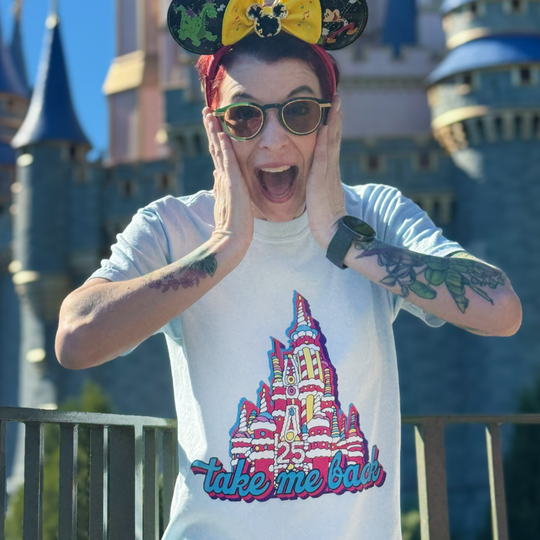 Take Me Back Cake Tee in White worn by a fan in Minnie ears, hands on cheeks, in front of Cinderella Castle